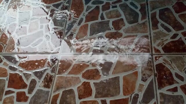 Heavy rain water flowing on brown natural stone tile texture background, rainy season