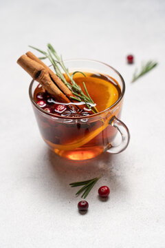 Hot winter drink with orange, cranberries, cinnamon, rosemary and spices in glass mugs, close up Christmas beverage