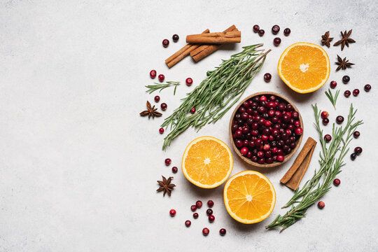 Ingredients for a cranberry orange winter drink with rosemary, cinnamon and spices on a light background with copy space