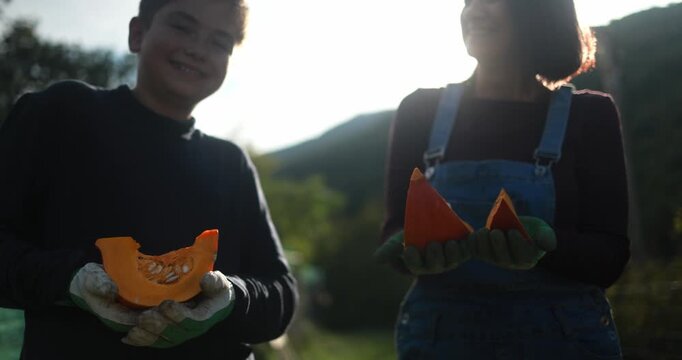 Mother and son holding organic pumpkin at house garden during fall season - Family lifestyle, food and autumn concept - UGC content