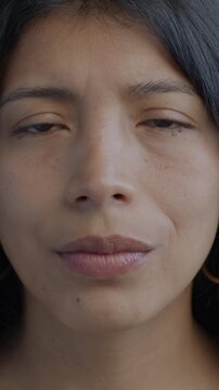 Close-up portrait of unhappy Hispanic lady looking at camera on black background. Negative emotion and miserable person concept.