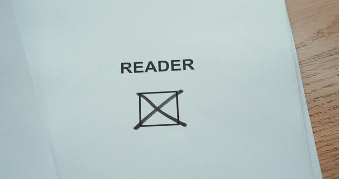 Close-up of a hand marking the reader checkbox on a paper form, representing reading habits, books and personal interests.