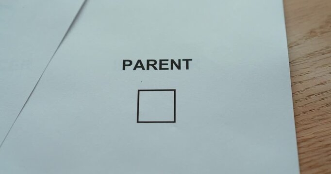 Close-up of a hand marking the parent checkbox on a paper form, representing parenthood, family status and childcare responsibility.