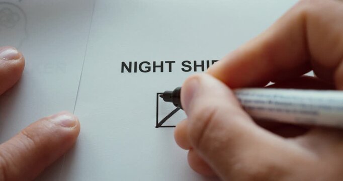 Close-up of a hand marking the night shift checkbox on a paper form, representing nighttime work and shift employment.