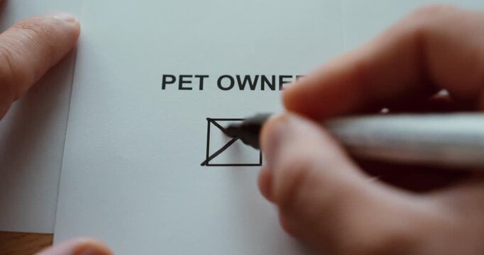 Close-up of a hand marking the pet owner checkbox on a paper form, representing pet ownership and animal care.