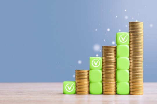 Ascending stacks of gold coins and green checkmark blocks showing growth progression on wooden table. Financial success, investment growth or business achievement concept with copy space.