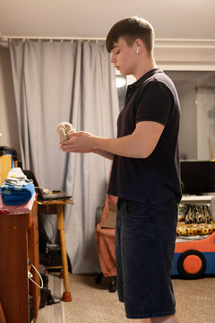 Young man standing indoors holding a small plush toy bunny in his hands in a casual room