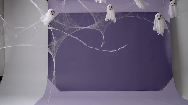 Swaying white ghosts drifting on purple backdrop, spider web arching as frames advance causing sway
