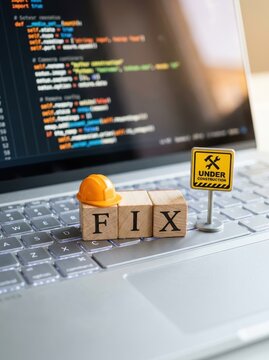 Software Maintenance and Website Debugging Concept with FIX Wooden Blocks and Construction Sign on Laptop Keyboard