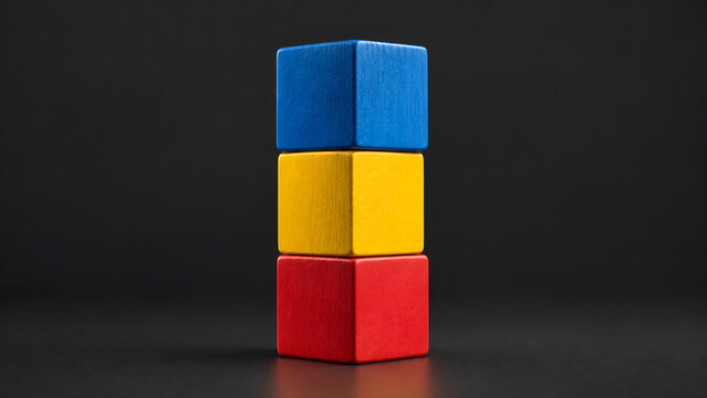 Three colorful wooden toy blocks stacked vertically in a tower on a dark background