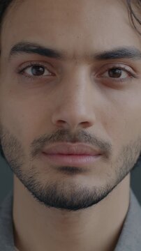 Close-up portrait of confident Middle Eastern man looking at camera with serious face on black background. Individuality and emotion concept.