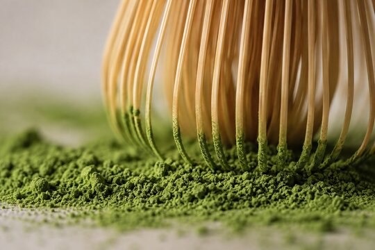 Macro view of bamboo tea whisk tines touching fine matcha powder in soft natural light