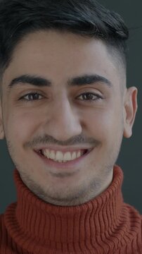 Slow motion portrait of joyful Middle Eastern man laughing looking at camera on black background. Positive emotion and fun concept.