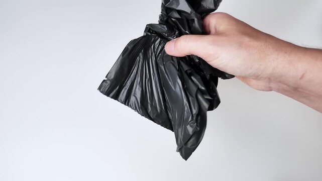 Hands are visible across three sections of the frame manipulating pieces of black trash bag material on a plain white surface, showing the action of handling plastic sheeting in sequence