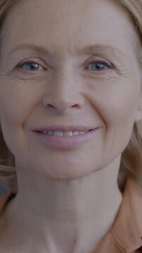 Slow motion portrait of cheerful mature woman smiling looking at camera on black background. Happy person and face expression concept.