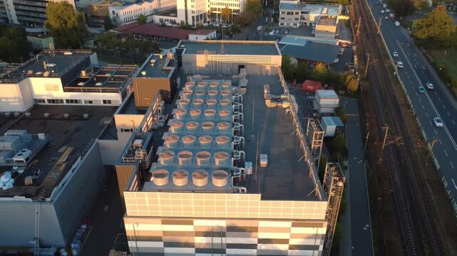 Drone approaching a Frankfurt data center and tilting down to reveal rows of rotating rooftop cooling fans. Filmed September 25, 2026.