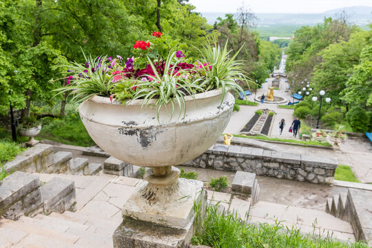 Ornamental stone planter filled with colorful flowering plants and spider plants overlooking wide stone stairs of Cascade Staircase of Zheleznovodsk, Russia