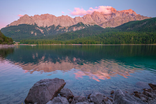 Peaceful blue hour twilight scene at Eibsee lake with the Zugspitze mountain peaks reflected in the still water in Berchtesgaden, Germany.