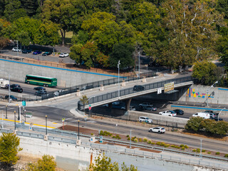 Obraz premium Aerial view shows vehicles driving along a multi lane freeway and overpass bridge near Old Sacramento State Historic Park with surrounding trees and roadways in Sacramento, California.
