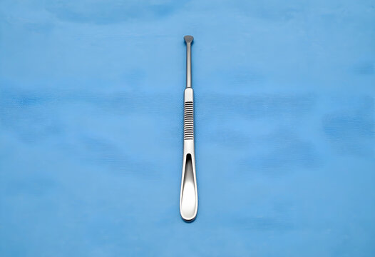 Surgery and medical procedure, surgical curette instrument for clinical operation and healthcare treatment on blue sterile fabric in hospital environment