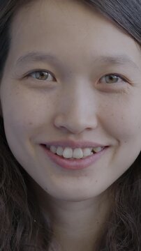 Close-up portrait of joyful Asian girl smiling looking at camera on black background. Positive emotion and young people concept.