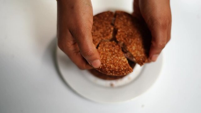 Hand Breaking Homemade Biscuit to Reveal Crisp Texture and Crumbs Close Up.