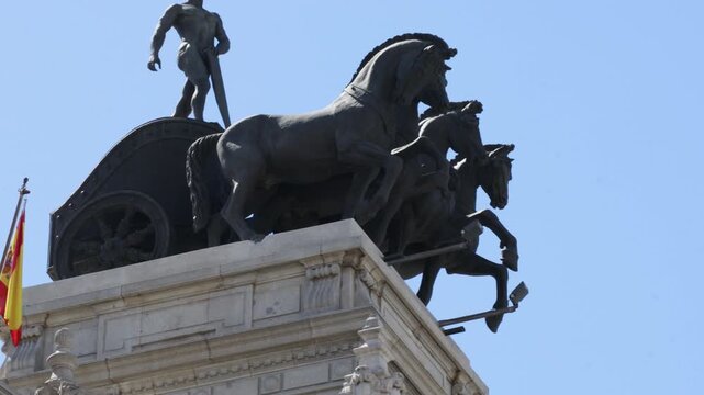 Close Up View Of The Bronze Quadriga Chariot Sculpture Atop The Bank Of Spain Building Against A Clear Blue Sky In Madrid, Spain. - low pan shot