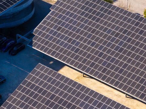 Aerial view of solar panels installed on a parking lot structure with cars parked underneath in Ancona, Marche, Italy.