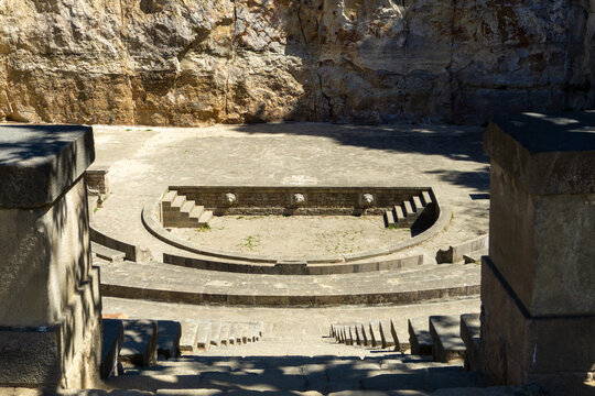 Ancient stone Teatre Grec amphitheater in Montjuic, Barcelona, featuring a semicircular stage, seating rows, and a rocky cliff backdrop, showcasing historical architecture and performance space