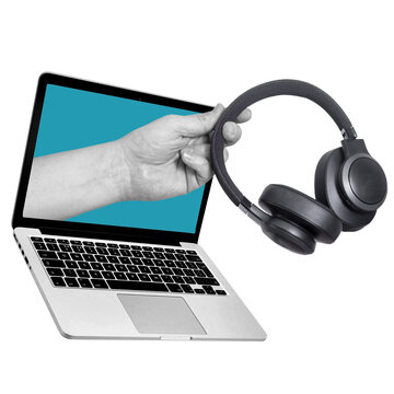 A hand reaches out to hold a pair of black headphones while positioned near an open laptop. The laptop's screen is blue. This scene highlights technology and sound devices.