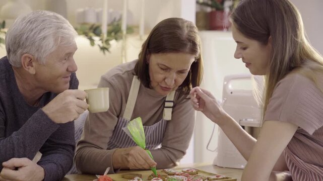 Family decorating Christmas gingerbread cookies with colorful icing cream