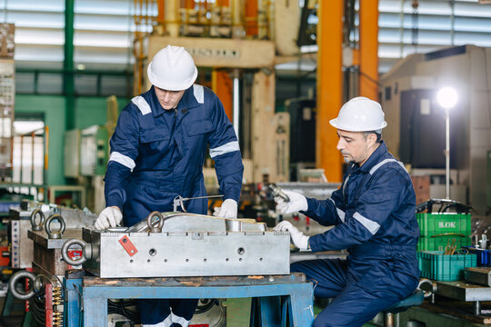 Professional engineer team worker training young man to service injection mold in die casting plant