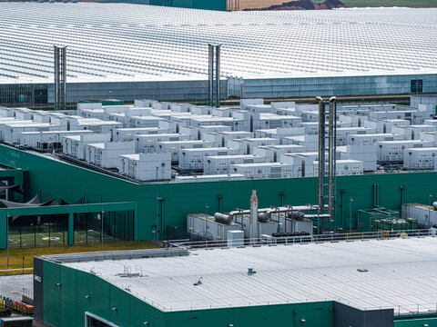 Aerial view of the Agriport A7 industrial facility with modular white units on the roof, green walls, and expansive greenhouses in Middenmeer, Noord-Holland, Netherlands.
