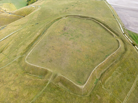 Aerial view of the Iron Age hillfort of Uffington Castle with its prominent earthwork ramparts and the nearby Uffington White Horse in the rolling hills of Faringdon, England, United Kingdom.