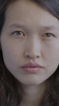 Close-up portrait of attractive Asian lady looking at camera with serious face on black background. People and facial expression concept.