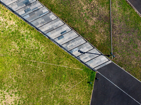 Aerial view of the Katowice International Conference Centre featuring a paved walkway cutting through a green roof with geometric lines and shadows Katowice, Wojewodztwo slaskie, Poland.