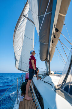 Man monitoring the mainsail while sailing a yacht offshore. Seamanship and navigation skills during a long distance voyage.