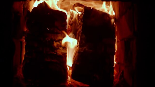 Close-up view of burning firewood logs inside a brick fireplace