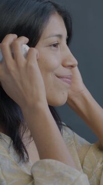 Joyful Hispanic lady putting on headphones listening to music dancing on black background. Modern technology and entertainment concept.
