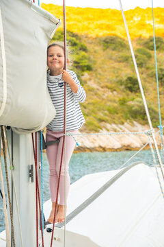 Young girl handling rope and exploring rigging on sailing yacht in Croatia. Practical sailing experience develops confidence, independence and seamanship skills in childhood