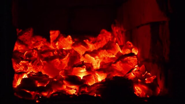Close-up of glowing hot embers and burning wood in a fireplace