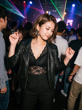 クラブのレーザー照明の中で音楽に合わせて踊る笑顔の若い女性