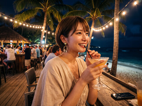 夜のビーチバーでカクテルを楽しむ笑顔の若い女性