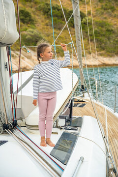 Young girl holding rope on sailing yacht near Croatian coast. Childhood sailing experience encourages practical learning, confidence and connection with the sea