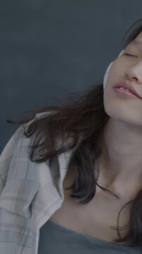 Carefree Asian woman listening to music with headphones dancing on black background. Happy person and modern technology concept.