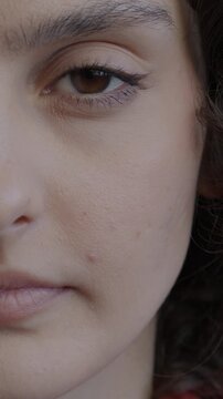 Close-up of young lady half face looking at camera against black color background. Emotion expression and real person concept.
