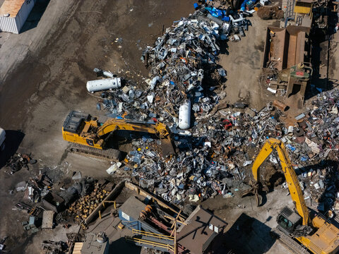 Aerial view of excavators sorting through large piles of scrap metal at a recycling facility in Carson, California, United States.