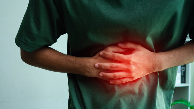 Close-up of a person clutching the abdomen with a red highlighted pain area, illustrating stomach ache, abdominal discomfort, digestive problems, inflammation, and gastrointestinal health concerns.