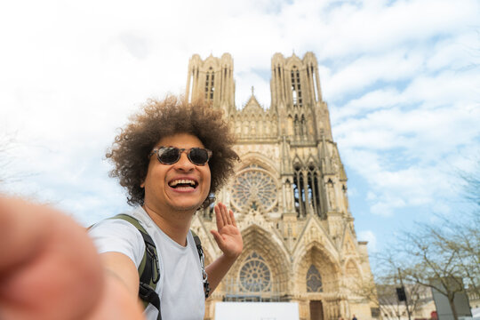 Happy traveler taking selfie at Reims Cathedral in France