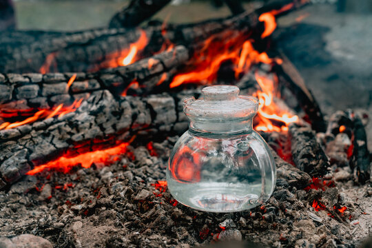 Glass teapot heat water over forest campfire